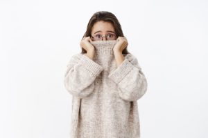 Shy woman pulling sweater up over nose